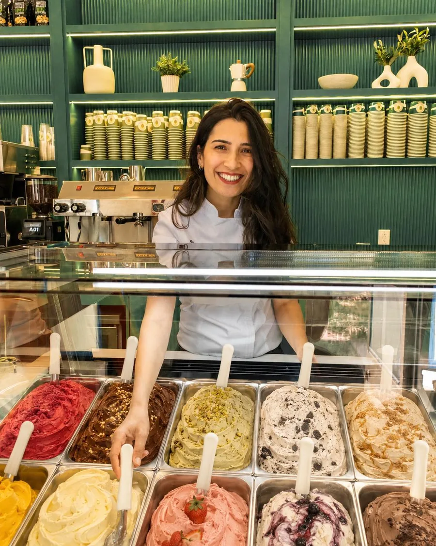 Culinary Director Jiyan Tekmenuray smiling behind the gelato case, reaching for a pan