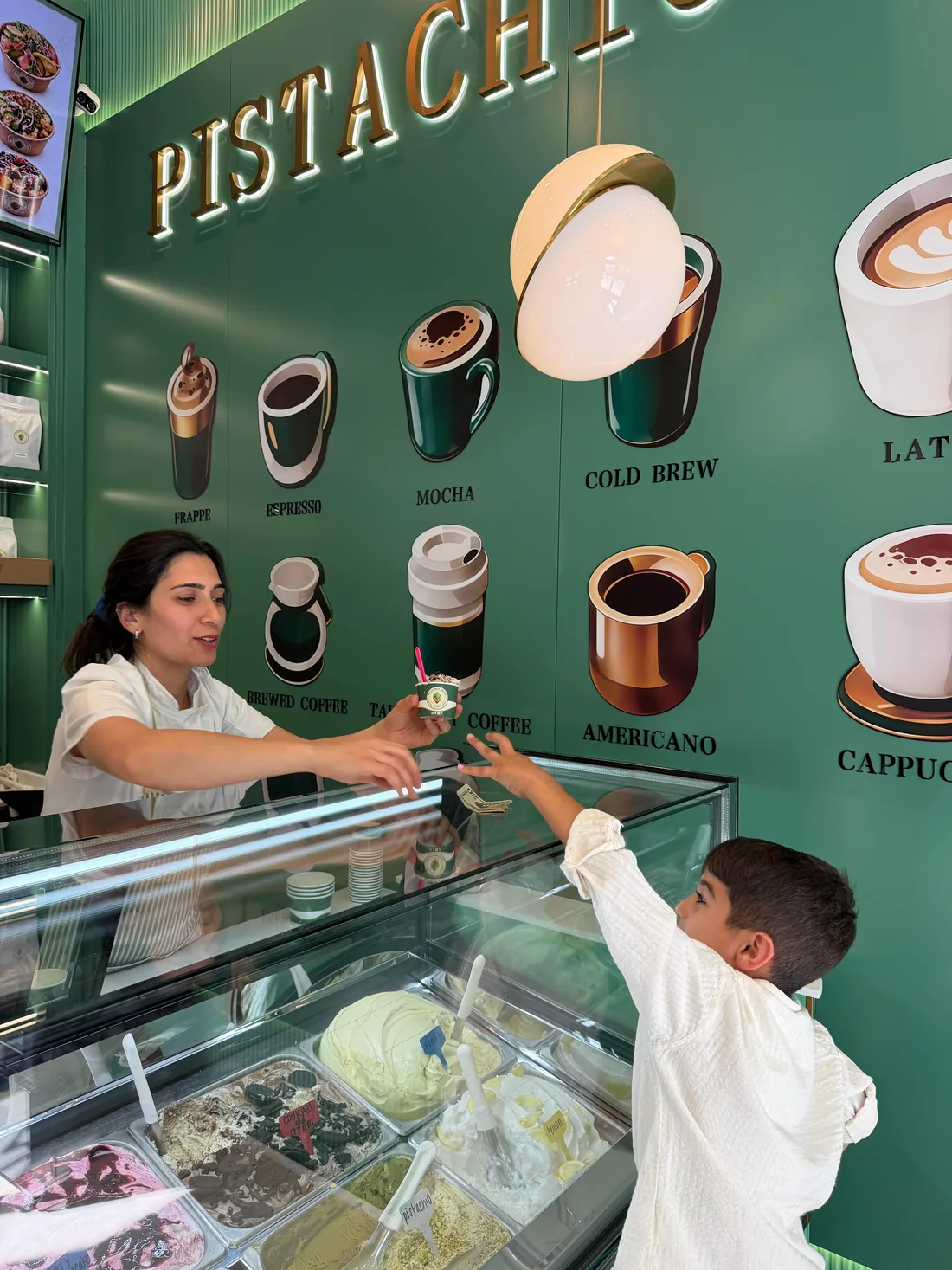 A server handing gelato across the counter to a young guest